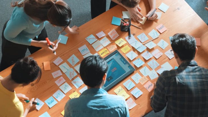 Top view of manager writing idea on sticky notes and explain idea. Symposium.